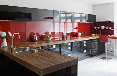 a bold red and black contemporary kitchen with a glossy backsplash and butcherblock countertops plus stainless teel appliances is very bold and cool
