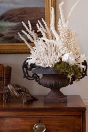 a vintage urn filled with corals and moss is a creative and cool piece to decorate an entryway, a living room or some other room