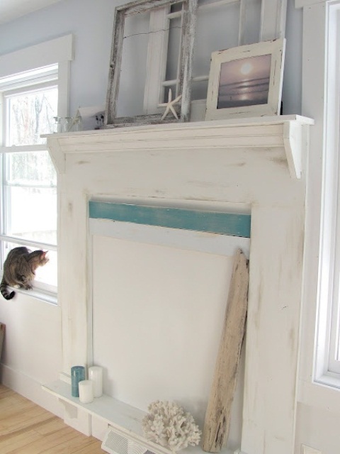 Starfish, frames, a beachy artwork, corals and blue and white candles in the non working fireplace