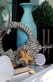 seashells, starfish, a fabric wreath, a blue vase, a crochet art for a simple and relaxed beach mantel