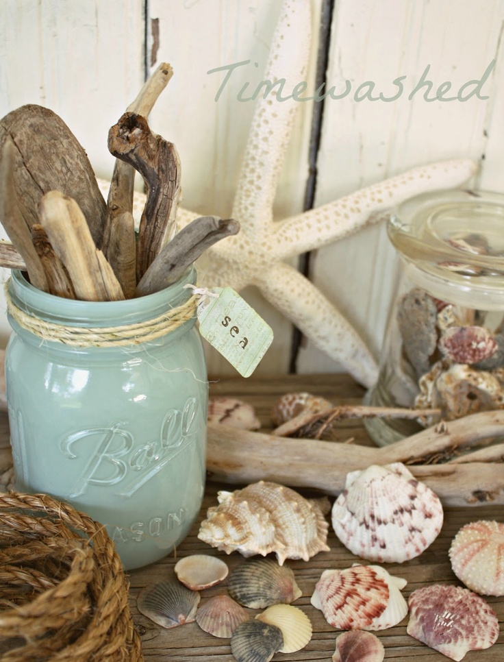 A mantel with seashells, starfish, jars with driftwood and seashells, rope looks beach like and very enjoyable