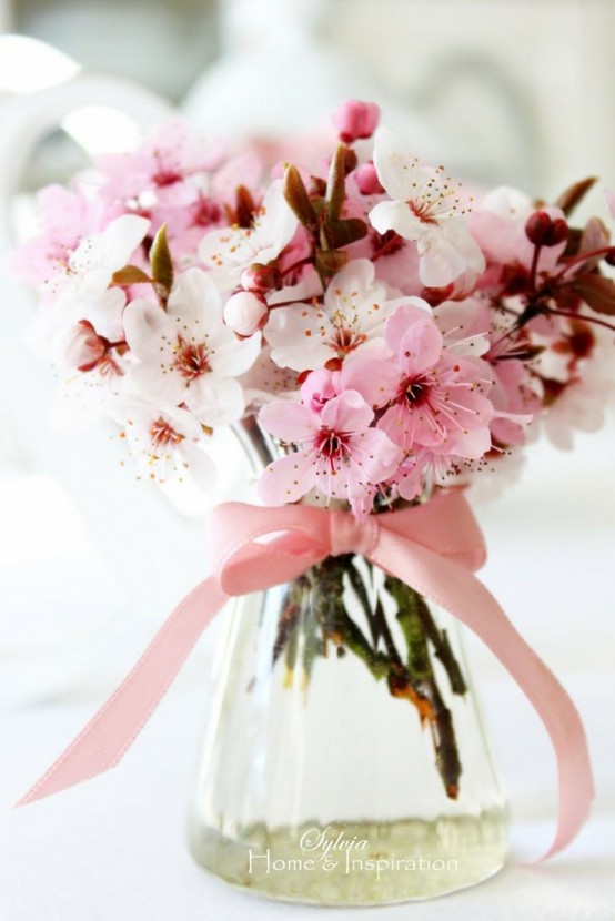 a clear vase with cherry blossom branches and a pink bow is a chic and bold centerpiece