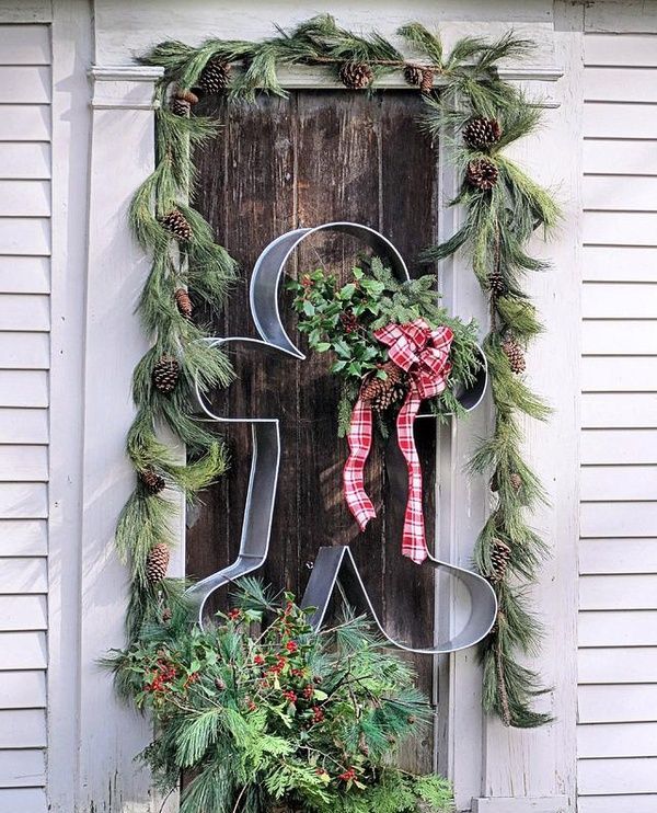An alternative to a Christmas wreath   a metal gingerbread man cookie cutter with a burlap scarf and evergreens
