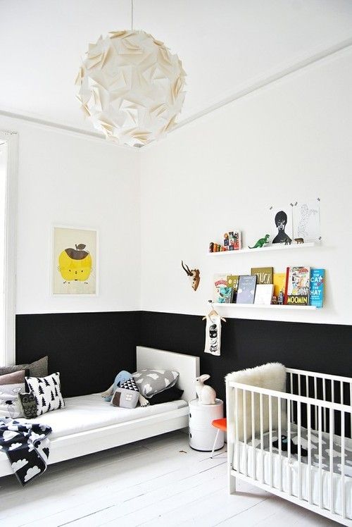 a Nordic black and white nursery with floating shelves, a crib and a bed and a half black wall