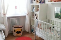 a neutral nursery with red and yellow touches, some bright toys and artworks, a storage basket