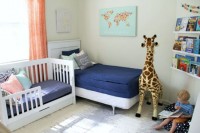 a bright nursery with beds standign next to each other, some bright touches and floating shelves