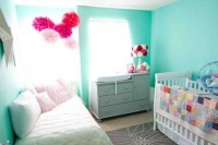 a bright turquoise nursery with white beds, bright paper hangings and colorful bedding