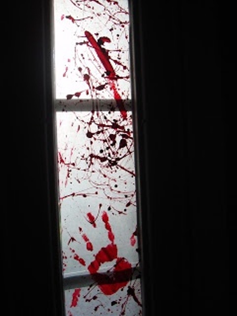 a glass door decorated with bloody hand marks and blood splatters is a great idea for a Dexter-theme or blood-themed party