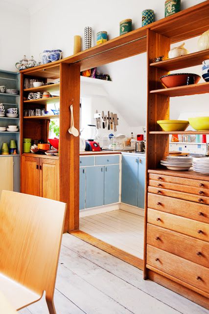 A pretty mid century modern stained shelving unit with drawers separates the kitchen and the dining space and gives some storage space to both areas