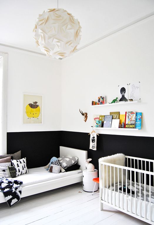 a small Nordic kid's room with color block walls, a bed and a crib, open shelves, lots of printed pillows and various books and toys