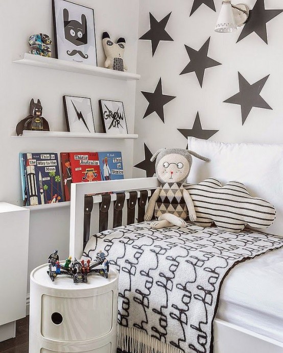 a laconic kid's room with a star accent wall, ledges for books and artwork, a white bed that can be transformed into a sofa and a small white nightstand