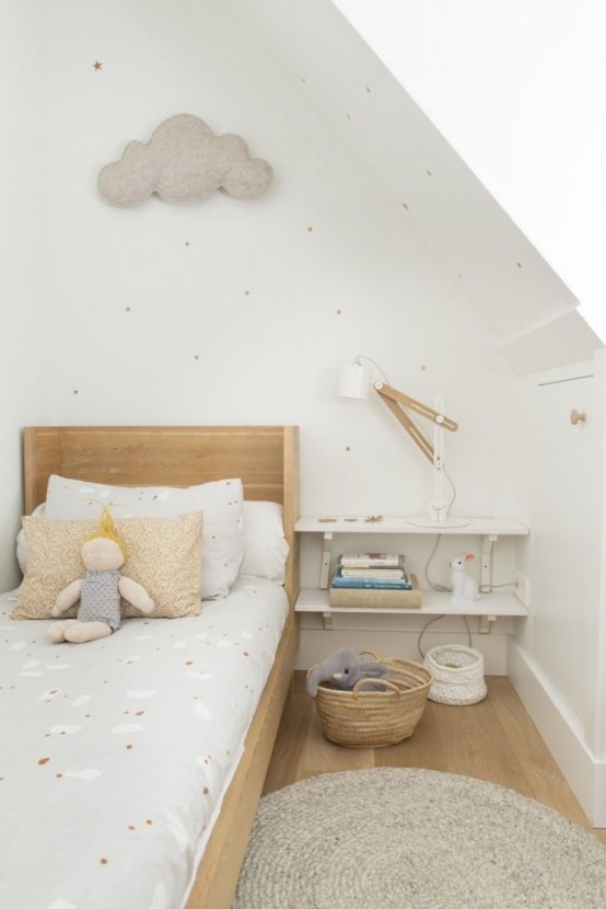 a delicate and subtle Scandinavian kid's room with a light-stained bed and neutral bedding, an open shelf nightstand, a cloud decoration and a white sconce and pastel bedding