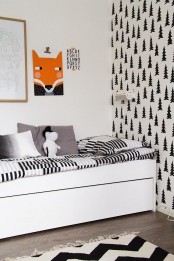 a black and white Nordic kid’s room with an accent printed wall, a white bed with monochromatic bedding, a gallery wall with a bright fox art