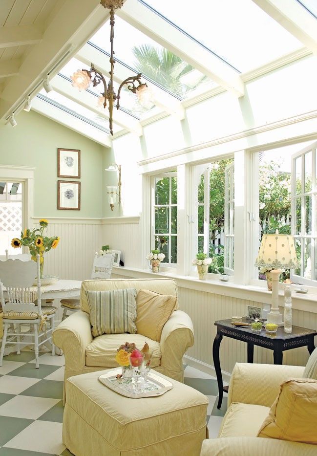 A neutral vintage sunroom with elegant and refined furniture in pastels, pendant lamps, lamps on the tables and much light