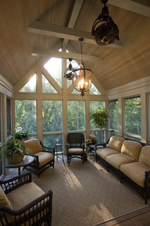 A vintage inspired sunroom done in tan and beige, dark rattan furniture and pendant lamps and chandeliers