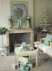 a pastel vintage living room with refined vintage holiday decor – a small tabletop tree with green and silver ornaments, a frozen light blue wreath and potted plants with icicles hanging on them