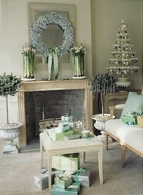 A pastel vintage living room with refined vintage holiday decor   a small tabletop tree with green and silver ornaments, a frozen light blue wreath and potted plants with icicles hanging on them