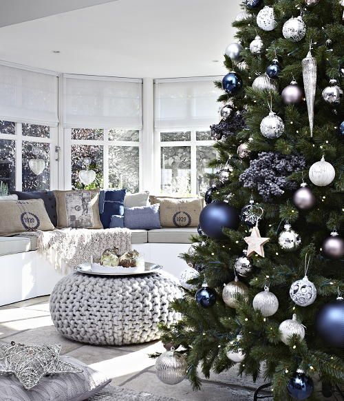 a Christmas tree with white, silver and blue ornaments, star and usual pillows in the same colors for a holiday feel in the room