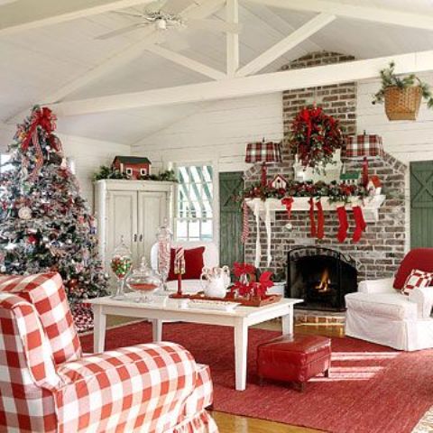 a traditional red and white Christmas living room with red stockings, a wreath with red bows over the fireplace, a frozen Christmas tree with red and white decor is lovely