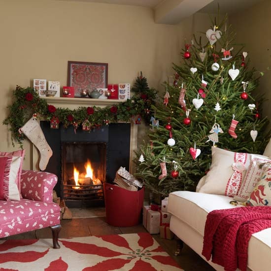 a fir garland with red blooms, a Christmas tree with white and red ornaments and a red blanket create a cool holiday mood in the space