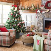 a rustic living room with bold Christmas decor – a red pillow, a berry wreath and a Christmas tree with catchy red and white ornaments plus a red garland with bold touches