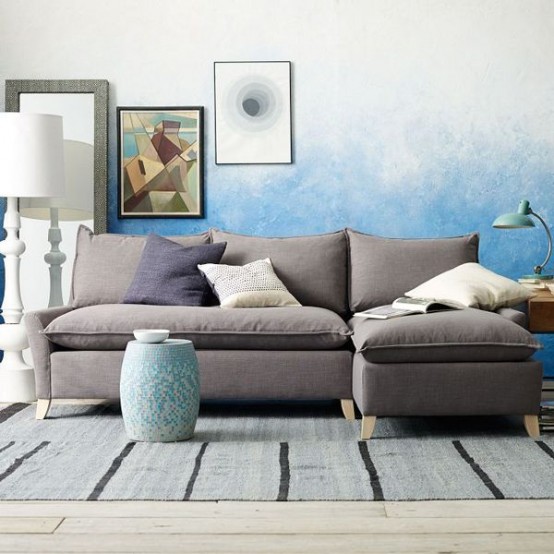 a catchy living room with a blue ombre walls, a taupe sofa with neutral pillows, a floor lamp and a mini gallery wall