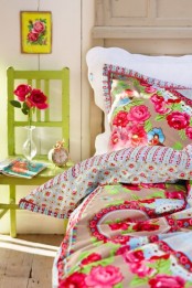a colorful bedroom with vintage furniture, colorful printed bedding, bold blooms and a green chair is welcoming and cool