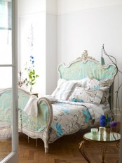 a refined bedroom with a chic vintage bed in blue, with floral bedding, lamps, blooms and candles