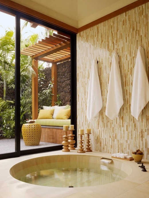 a tropical bathroom done in neutrals, with a round sunken bathtub and sliding doors to the garden for a view and more sunshine