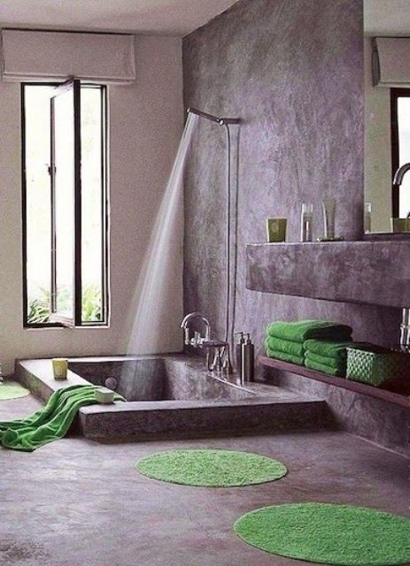 A wabi sabi bathroom with shelves and a vanity of concrete and a sunken bathtub plus a pivot window to let some light inside