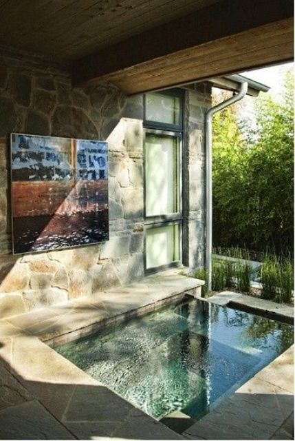 an indoor-outdoor bathroom with a sunken bathtub or pool, done with stone and tiles plus sunshine coming from outside