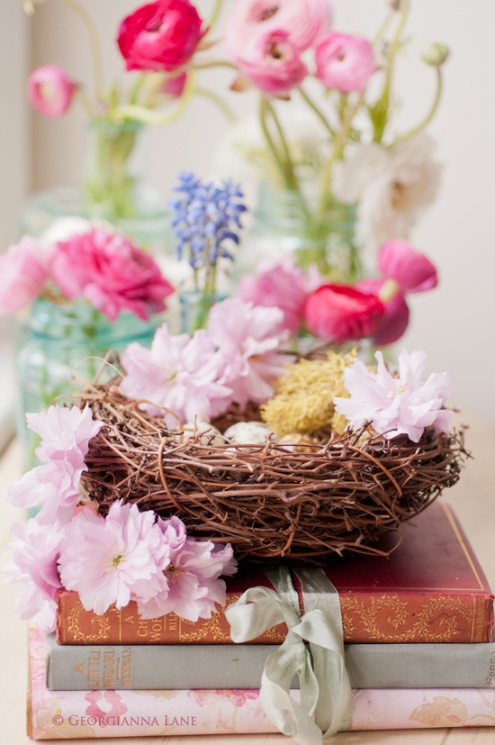 a nest with pink blooms and faux eggs is a cool idea of an Easter centerpiece