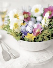 a bowl with grass, spring blooms and pastel speckled fake eggs for Easter
