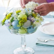 a glass bowl with pastel eggs and pastel spring blooms is a chic Easter centerpiece