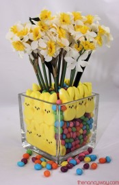 a clear vase with yellow bunnies and candies and yellow daffodils for an Easter centerpiece