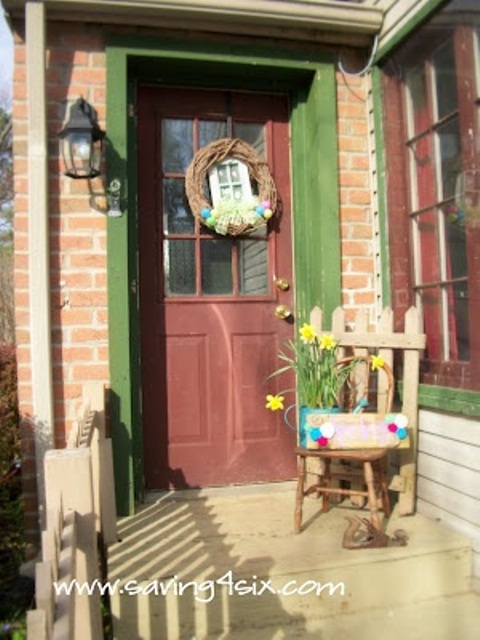 bright Easter porch styling with a colorful egg wreath, spring daffodils in a watering can and a colorful crate