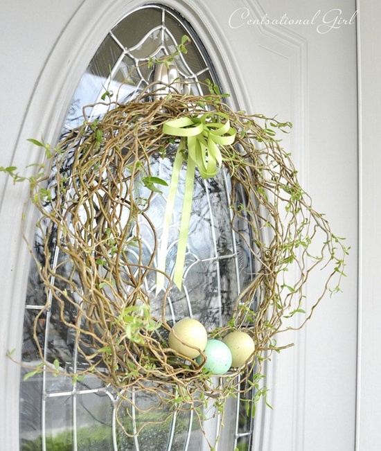 a fresh and green Easter wreath with colorful eggs in it and a bow on top