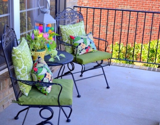 a duo of chairs with colorful pillows, a lantern with colorful eggs and bright blooms in a pot