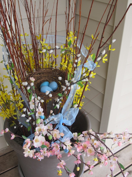 a spring arrangement with spring blooms and blooming branches and a fake nest plus eggs