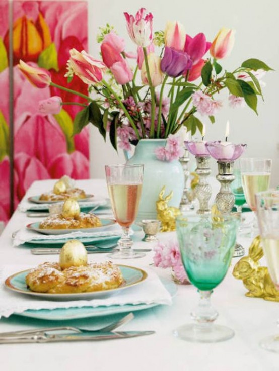 a modern pastel Easter tablescape with aqua-colored porcelain, turquoise glasses, bright tulips and little bunnies, white napkins is a chic table setting