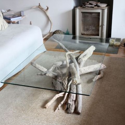 a refined modern coffee table made of driftwood for the base and a sheer glass top to enjoy this wood through it