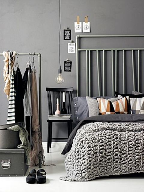 a modern grey bedroom with makeshift closet of piping, a bed with an extended pipe headboard and some boxes
