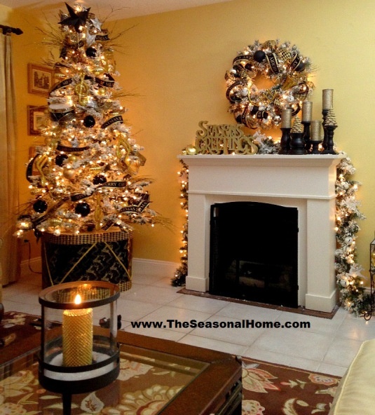 elegant black and gold holiday decor with a pretty flocked Christmas tree decorated with lights, ribbons and black and gold ornaments and a mantel with a matching wreath and gold candles in black candleholders