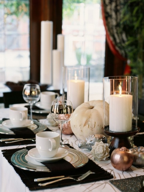 a stylish black and white Thanksgiving tablescape with black placemats, white candles, pumpkins and porcelain, copper gourds and pumpkins is pure chic