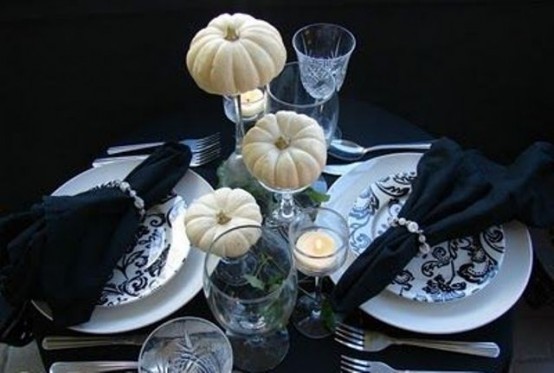 a refined black and white Thanksgiving tablescape for two, with patterned plates and black napkins, white pumpkins and greenery is cool