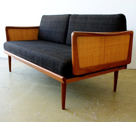A mid century modern sofa with a stained frame, rattan armrests and black upholstery will be a nice solution for both indoors and outdoors