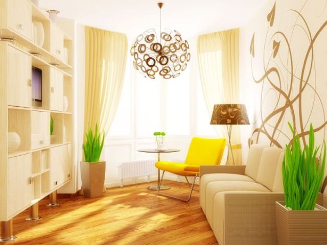 A small bright living room with a white wall taken by a storage unit, a sofa, a yellow chair, potted greenery and a sphere lamp