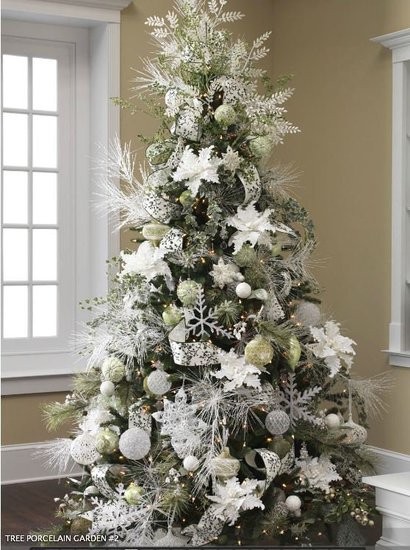 a Christmas tree with white and silver ornaments - balls, snowflakes, stars, snowy greenery and shiny ribbons