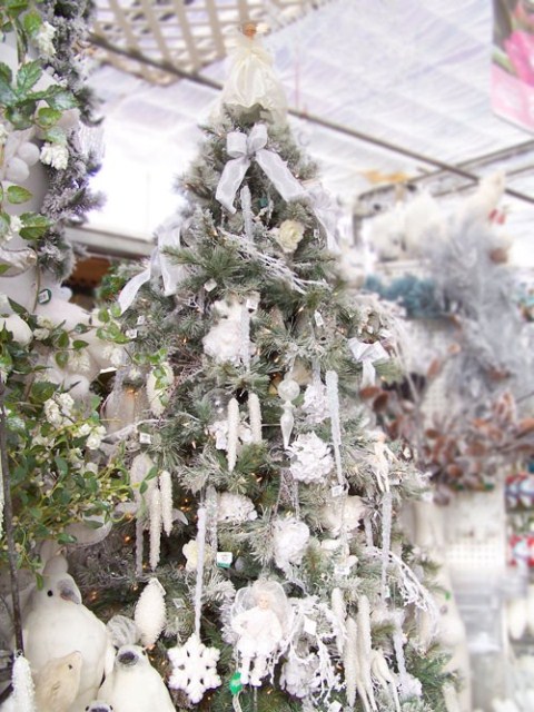 a snowy Christmas tree with snowflake and other ornaments, icicles and bow ornaments in silver and white