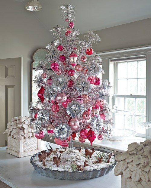a silver Christmas tree with pink and red ornaments and deer figurines under the tree